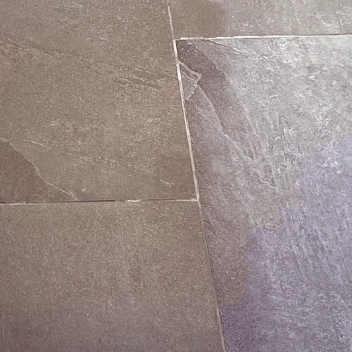 Porcelain floor tiles with a dusty film of builders' dust next to a cleaned strip