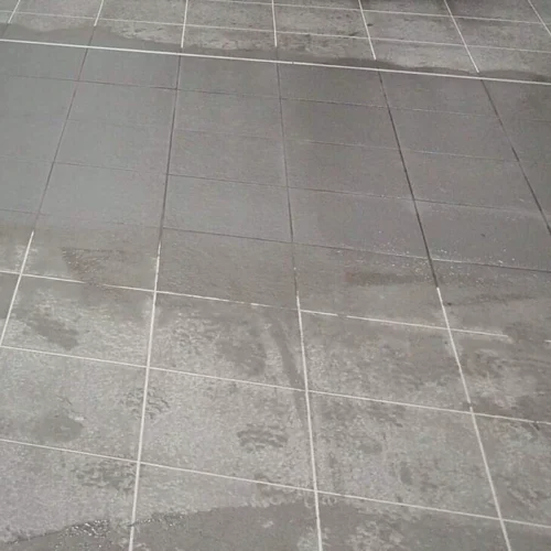 Grey porcelain floor tiles covered in a cloudy, smeared grout haze film